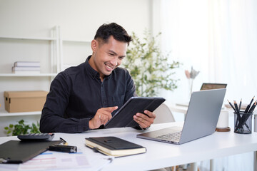 Smiling professional businessman checking information online on digital tablet during work.