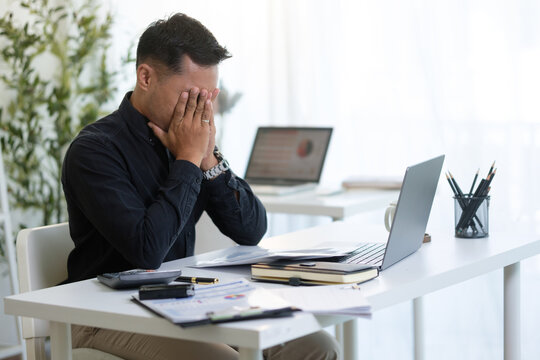 Overworked entrepreneur managing tasks and feeling pressure while working on a laptop in an office.