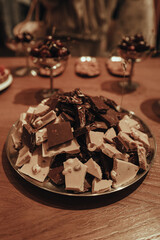 White and dark broken chocolate pieces, delicious and sweet dessert on a wooden table