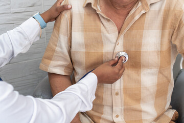 Doctor visiting elderly patient at home and checking heartbeat
