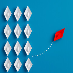 One red paper boat breaks away from a group of white paper boats on a blue background