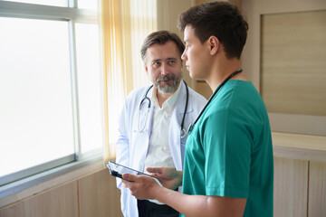 Senior man doctor discuss with young male doctor, giving advice and sharing ideas in a hospital...
