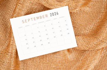 September 2026 calendar card on golden color textile background.
