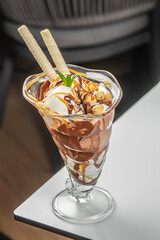 A decadent ice cream sundae served in a tall glass with scoops of vanilla and chocolate ice