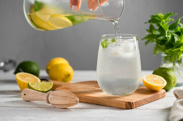 Pouring homemade lemonade drink made from lemons, limes and fresh mint.