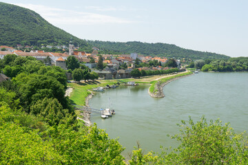 Obraz premium A high angle panoramic view of hainburg an der donau, showcasing the towns buildings along the danube river with docked boats and a verdant hillside, concept of european travel.