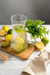 A glass jug with lemonade with lemons, limes and fresh mint, summer drink