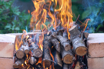 Firewood burns in the hearth of an outdoor stove.