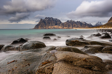 Rocky Shoreline and Mountains under Cloudy Sky