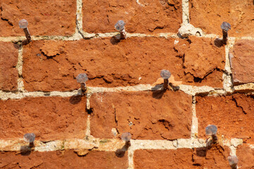 Background of old, antique brick. Brick wall with rusty nails for creating exterior decor.