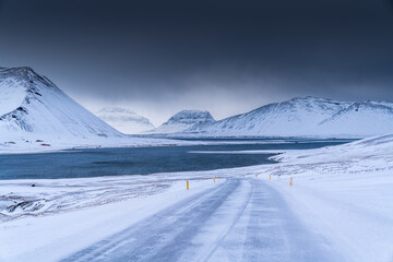 Snowy Road Leading to Frozen Lake and Mountain Range