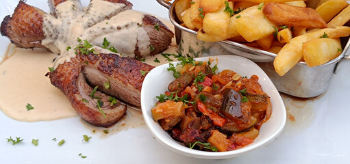 magret de canard, légumes et frites dans une assiette