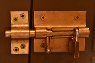 “Close-up of metal sliding bolt lock on wooden door—symbolizing security, craftsmanship, and...