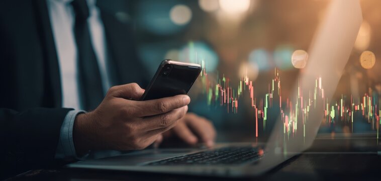 The businessman analyzes stock market trends using a smartphone and laptop.