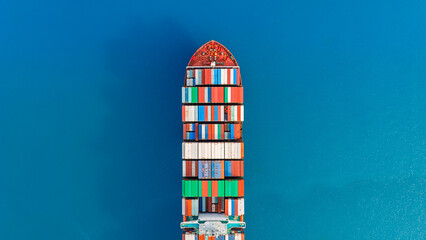 Aerial top view large container ship sailing hi- speed in the blue sea.