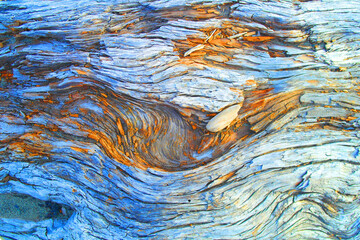 Still life of small pebble in a weathered wooden log with wavy lines 
