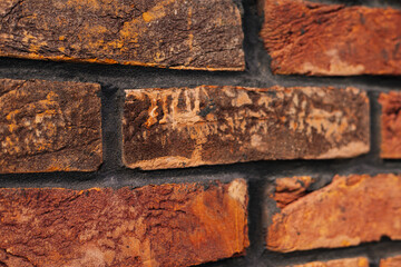 A textured brick wall, showing rich red and brown hues and a rough surface. Close-up of a rustic brick wall, showing the textured surface and warm color variations. Ideal for backgrounds.