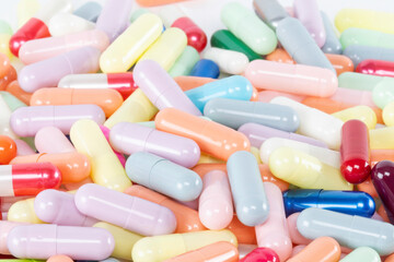 A background of many soft, pastel color pills and capsules. A pharmacy or healthcare texture...