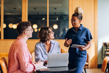Three coworkers discussing tasks together in a modern office environment