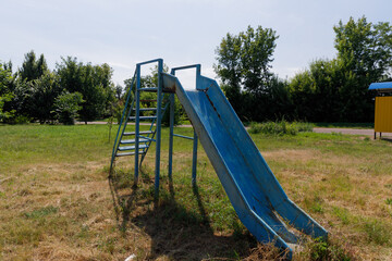 Fototapeta premium A Vibrant Blue Slide in a City Park Surrounded by Greenery Inviting Joy and Playfulness for Children and Families Enjoying the Outdoors on a Sunny Day