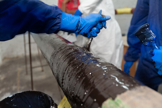 A service worker applies epoxy coating to a fiberglass repair sleeve to restore the load-bearing capacity of a pipeline.