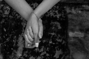 Black and white photo of two female hands holding with matching silver bracelets