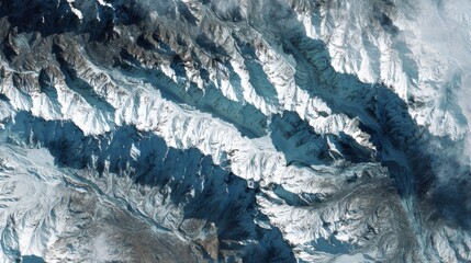Snow-covered mountain range with rugged peaks and deep valleys, captured from an aerial or satellite perspective.