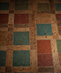 Colorful geometric patterns create a vibrant patchwork on an aged wooden floor in a cozy room
