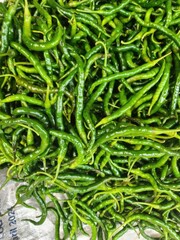 Close-up view of a large pile of fresh green chili peppers.