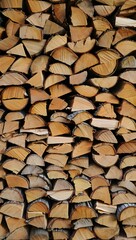 Stacked firewood creates a rustic texture, ideal for heating homes and providing warmth during the...