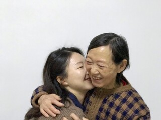 A warm intergenerational embrace between grandmother and granddaughter, Joyful smiles and gentle...