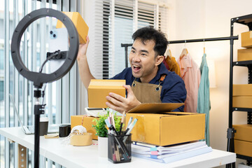 A man is selling clothes online, using his mobile phone. He is live selling with fun. He is smiling...
