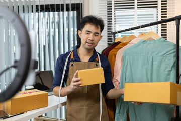 A man is selling clothes online, using his mobile phone. He is live selling with fun. He is smiling...