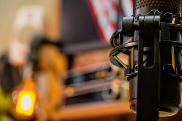 Modern home office desk setup with American Independence Day theme, including monitors displaying US flag wallpaper, bonsai tree, microphone, and warm cozy lighting ambiance.