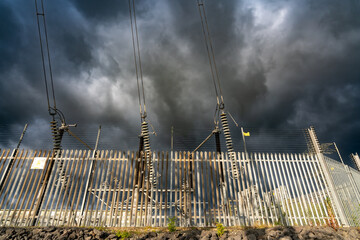 Security fence around a power station with dramatic dark clouds overhead