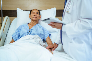 Doctor and nurse visit elderly male patient in recovery ward in hospital.