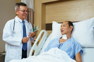 Doctor and nurse visit elderly male patient in recovery ward in hospital.