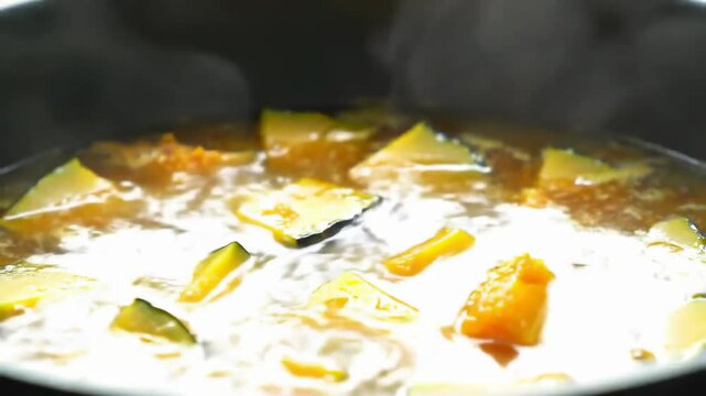 Warm pumpkin soup cooking in a pot with vegetables and steam  