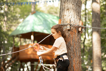 Little cute girl child having fun at adventure park. Kids climbing in a rope park. Children summer...