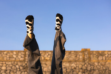 Legs in the air wearing cow print socks on blue sky background, outdoor scene.
