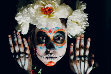 Woman with mexican skull halloween makeup on face. Day of the dead aka Dia de los Muertos and...
