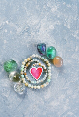 set of crystals, beads of minerals, paper heart on blue-grey background. Magic, esoteric spiritual practice for life balance, soul relax, harmony, love. witchcraft, mystery ritual with gemstones