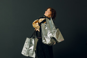 Portrait of a young adult woman dressed in a medieval dress holding shopping bags in hands