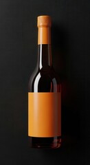 Shiny brown liquid bottle with orange label and cap sits against a dark textured backdrop