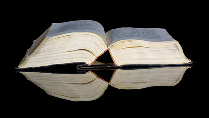 Old book owned on a black reflective surface
