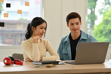 Young colleagues discussing a project together, showing teamwork, creativity, and friendly communication in the workplace