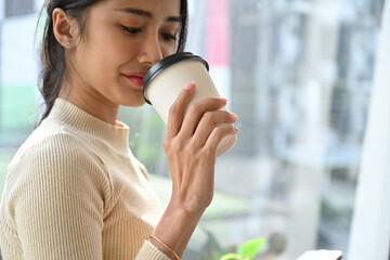 Close-up of a businesswoman savoring a warm coffee in a modern office, enjoying a peaceful break...