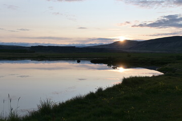 Paisaje con lago al atardecer con flores amarillas y montañas al fondo