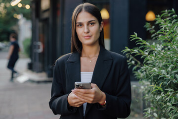 Business woman holding smartphone at city street