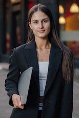 Woman in business suit holding laptop at the city
